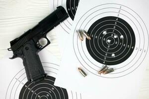 Gun and many bullets shooting targets on white table in shooting range polygon. Training for aiming and shooting photo