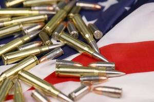 Many yellow 9mm and 5.56mm bullets and cartridges on United States flag. Concept of gun trafficking on USA territory or special ops photo