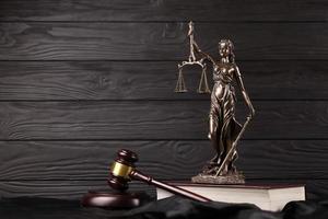 The Statue of Justice - lady justice or justitia the Roman goddess of Justice. Statue on brown book with judge gavel. Concept of judicial trial, courtroom process and lawyers work photo