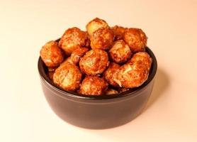 Selective focus of many candied macadamia nuts spinning in a small bowl. photo