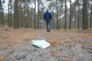 Young man loses his euro money bills on Russian autumn fir wood path. Carelessness and losing money concept photo