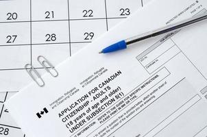 la solicitud de ciudadanía canadiense para adultos y el bolígrafo azul se encuentran en la página del calendario foto