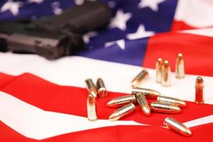 Many yellow 9mm bullets and gun on United States flag. Concept of gun trafficking on USA territory or shooting range photo