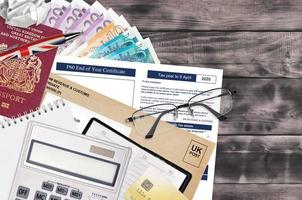 English Tax form P60 End of year certificate by HM revenue and customs lies on table with office items. HMRC paperwork and tax paying process in United Kingdom photo