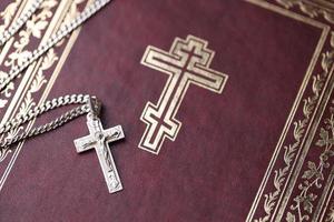 Silver necklace with crucifix cross on christian holy bible book on black wooden table. Asking blessings from God with the power of holiness, which brings luck photo