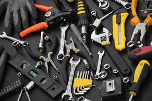 kit de herramientas de manitas en la mesa de madera negra. muchas llaves y destornilladores, apiladores y otras herramientas para cualquier tipo de reparación o trabajos de construcción. herramientas de reparador foto