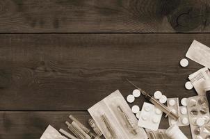Narcotic stuff with many pills and syringes lies on wooden table and ready to use photo