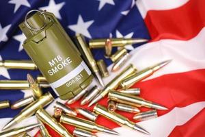 M18 smoke grenade and many yellow bullets and cartridges on United States flag. Concept of gun trafficking on USA territory or spec ops photo