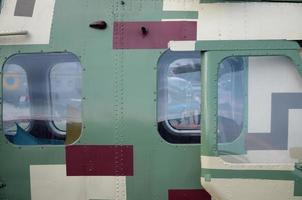 Helicopter cabin fragment close up. Camouflage aircraft fuselage and bulletproof glass photo