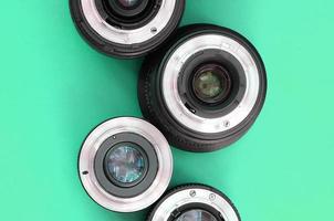 Several photographic lenses lie on a bright turquoise background. Copy space photo