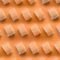 rollos filadelfia con salmón sobre fondo naranja. minimalismo vista superior patrón plano laico con comida japonesa foto