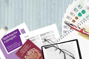 la guía violeta inglesa que solicita un pasaporte se encuentra en la mesa con artículos de oficina. Papeleo del pasaporte del Reino Unido foto