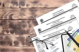 I-130 Petition for alien relative, I-485 Application to register permanent residence or adjust status and I-864 Affidavit of support under section 213A of the INA forms lies on table photo