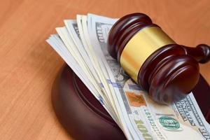Judge gavel and money on brown wooden table. Many hundred dollar bills under judge malice on court desk. Judgement and bribe photo