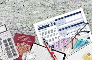 English Tax form P60 End of year certificate by HM revenue and customs lies on table with office items. HMRC paperwork and tax paying process in United Kingdom photo