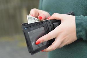 Woman hands with red nails holds black mens purse with many US hundred dollars bills. Concept of salary earnings or counting money photo