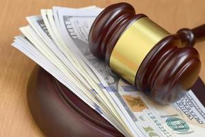 Judge gavel and money on brown wooden table. Many hundred dollar bills under judge malice on court desk. Judgement and bribe photo