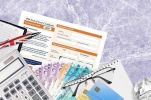 English Tax form P60 End of year certificate by HM revenue and customs lies on table with office items. HMRC paperwork and tax paying process in United Kingdom photo