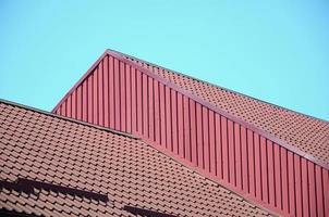 A fragment of a roof from a metal tile of dark red color. Quality Roofing photo