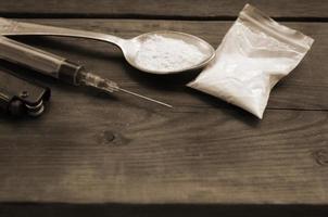 encendedor de jeringa y cuchara llena de polvo blanco sobre fondo de madera. concepto de adicción a las drogas heroína foto