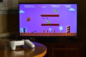 kharkov, ucrania - 12 de noviembre de 2020 controlador de videojuegos dendy en la mesa con el juego super mario bros en exhibición foto