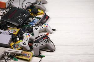 KHARKOV, UKRAINE - DECEMBER 27, 2020 Pile of old 8-bit video game consoles and many gaming accessories like joysticks and cartridges. Old school retro gaming photo