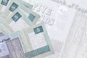 5 Egyptian pounds bills lies in stack on background of big semi-transparent banknote. Abstract business background photo