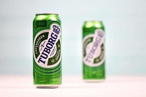 KHARKOV, UKRAINE - DECEMBER 8, 2020 Aluminium cans of green Tuborg beer on wooden background. Tuborg is Danish brewing company founded in 1873 photo