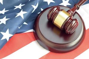 Justice mallet on United States flag in a courtroom during a judicial trial. Law concept and empty copyspace. Judge hammer photo