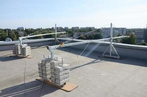 Counter weight or weight balance concrete blocks or bricks as part of suspended wire rope platform for facade works on high multistorey buildings. Many blocks with metal handles photo