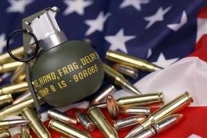 M67 frag grenade and many yellow bullets and cartridges on United States flag. Concept of gun trafficking on USA territory or spec ops photo