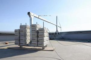 Counter weight or weight balance concrete blocks or bricks as part of suspended wire rope platform for facade works on high multistorey buildings. Many blocks with metal handles photo