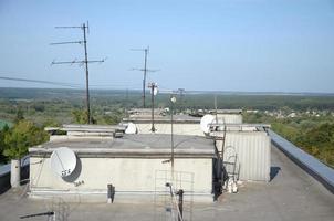 White satellite dish with three converters mounted on residental building rooftop concrete wall. Satellite television photo