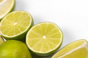 Many halves and slices of yellow lemon and green lime on light white table. Fresh fruits on kitchen wooden top photo