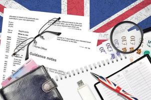 English form BRP with guidance notes to applying biometric residence permit card from UK visas and immigration services lies on table with office items. UK residence permit paperwork photo