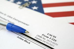 I-526 Immigrant Petition by Alien Entrepreneur blank form lies on United States flag with blue pen from Department of Homeland Security photo