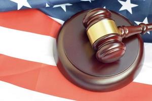 Justice mallet on United States flag in a courtroom during a judicial trial. Law concept and empty copyspace. Judge hammer photo