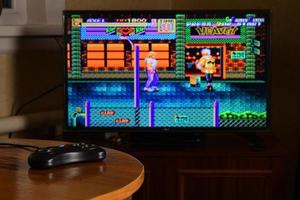 KHARKOV, UKRAINE - NOVEMBER 12, 2020 Sega mega drive video game controller on table with Streets of Rage 2 game on display photo