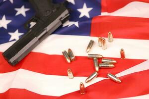 Many yellow 9mm bullets and gun on United States flag. Concept of gun trafficking on USA territory or shooting range photo