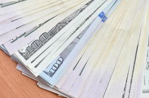 Fan of many one hundred and fifty dollar bills on wooden background surface close up. Flat lay top view. Abstract business concept photo