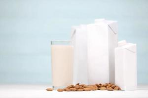 vaso de leche de almendras con nueces de almendras sobre tela de lona sobre mesa de madera blanca. leche alternativa láctea para desintoxicación, alimentación saludable y dietas foto