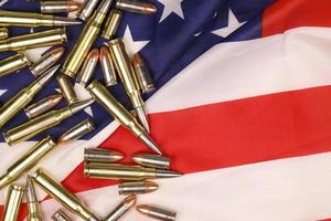 Many yellow 9mm and 5.56mm bullets and cartridges on United States flag. Concept of gun trafficking on USA territory or special ops photo