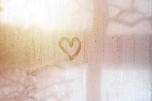 The heart is painted on the misted glass in winter photo