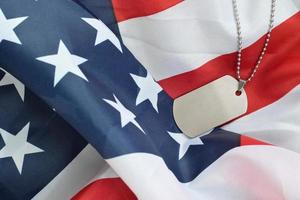 Cuentas militares plateadas con etiqueta de perro en la bandera de tela de los Estados Unidos foto