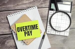overtime pay words and green sticker on wooden background photo