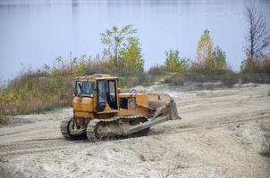 agregado de cantera con maquinaria pesada. Excavadora de oruga con retroexcavadora que conduce a la cantera del sitio de construcción foto