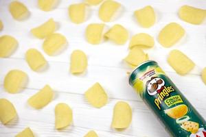 queso pringles sabor cebolla. lata de tubo de cartón con papas fritas pringles sobre mesa blanca. pringles es una marca de papas fritas propiedad de la compañía kellogg foto