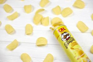 Pringles cheesy cheese flavour. Cardboard tube can with Pringles potato chips on white table. Pringles is a brand of potato snack chips owned by Kellogg Company photo