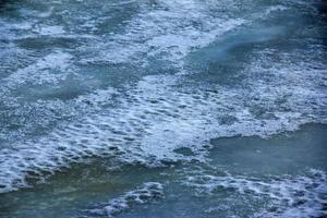 Winter background of the icy surface of the river. Texture of ice covered with snow. photo