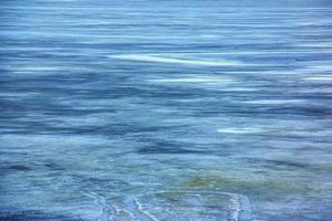 Winter background of the icy surface of the river. Texture of ice covered with snow. photo
